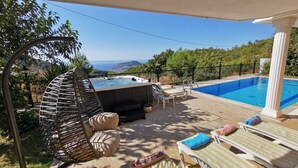 Una vasca idromassaggio con poltrona relax, una piscina e vista sul mare.