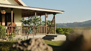 Una casa con porche, baranda de madera y vistas a las montañas.