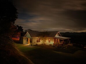 Ett tvåvåningshus med ett sluttande tak, en veranda och ett litet uthus som är sammanbyggt med huset.