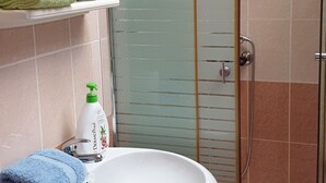 A bathroom with a glass-enclosed shower, a sink with a towel, and a mirror. - Cozy Studio Retreat in Vrnjacka Banja (Vrnjacka Banja)