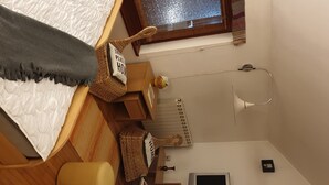 A bedroom with a bed, two chairs, a desk, a radiator, and a lamp. - Cozy Studio Retreat in Vrnjacka Banja (Vrnjacka Banja)