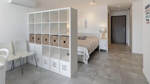 Une chambre moderne avec un lit, une armoire blanche, un bureau et une chaise.