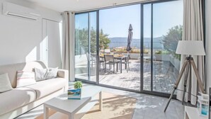 Un salon moderne doté d’une grande porte-fenêtre coulissante donnant sur une terrasse extérieure.
