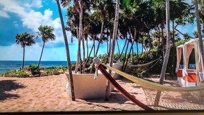 Una playa con una hamaca, palmeras y una silla de playa.