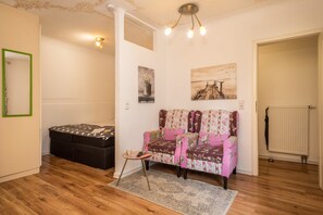 A room with a sofa, a small table, a radiator, and a ceiling light fixture.