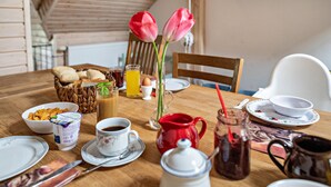 Een ontbijttafel met brood, ontbijtgranen, koffie en een kan sap.