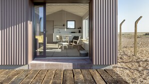 A modern, minimalist interior with a glass door leading to a dining area and kitchen. - Radar by Bloom Stays - sleeps 4 on nature reserve (Dungeness)