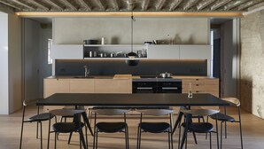 A modern kitchen with a central island, built-in appliances, and a dining area with a long table and chairs. - Pump Station by Bloom Stays in Dungeness - stunning location (Dungeness)