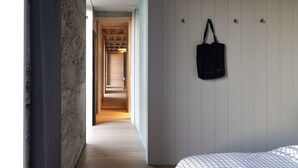 A bedroom with a bed, a hanging bag, and a hallway leading to another room. - Pump Station by Bloom Stays in Dungeness - stunning location (Dungeness)