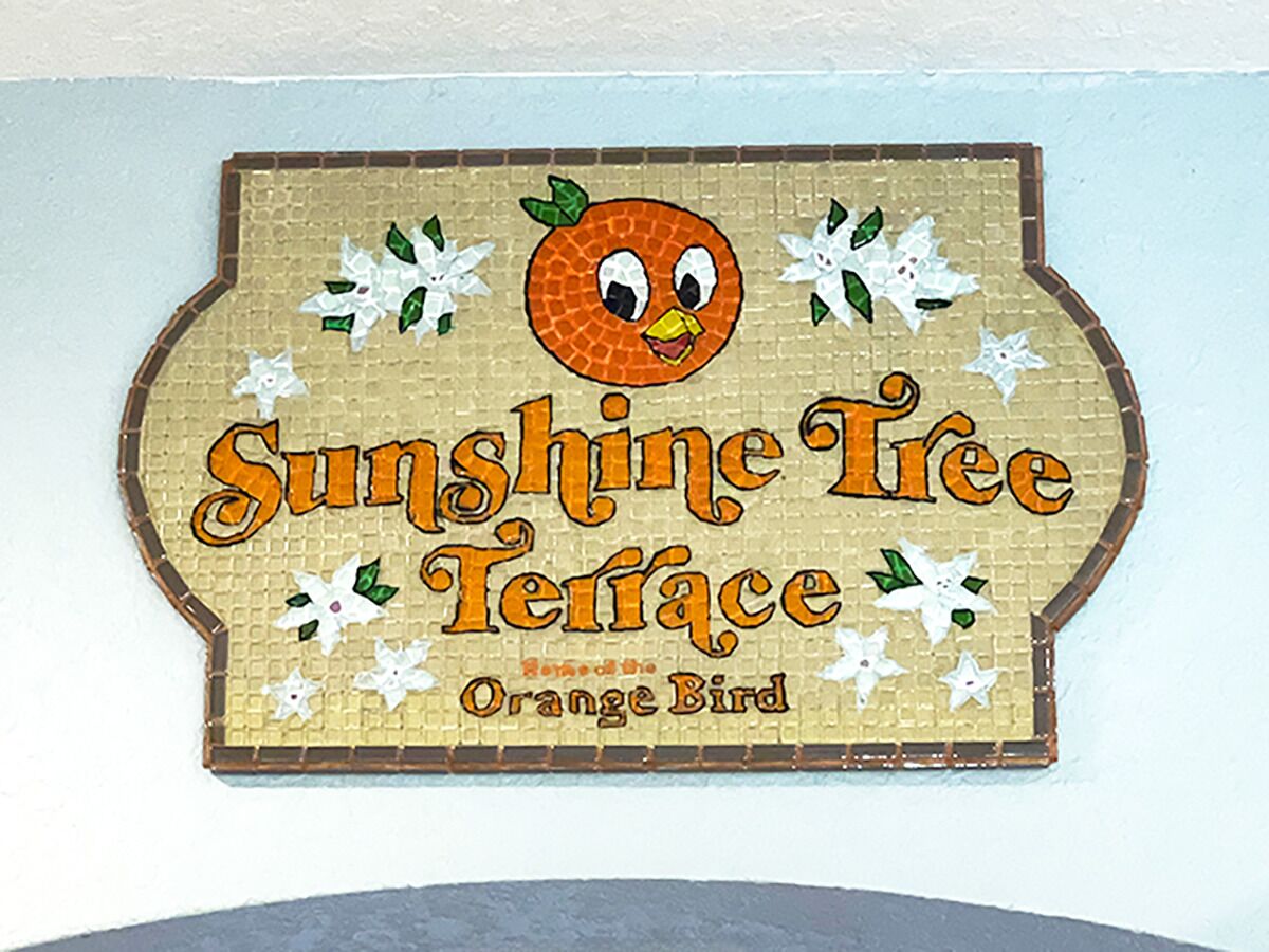 A wall sign with the text "Sunshine Tree Terrace" and an illustration of an orange bird.