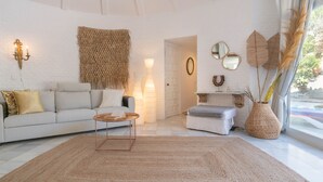 A living room with a white brick wall, a sofa, a coffee table, a side table, and a window with curtains. - Pool Villa Rancho Domingo family friendly, Benalmádena, Spain (Benalmádena)
