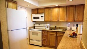 A kitchen with wooden cabinets, a white refrigerator, a microwave, a stove, and a granite countertop. - 1 BR Condo 1406L - 2 blocks off beach with great Ocean and Intercoastal Views. (Fort Lauderdale)