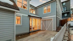 Ett tvåvåningshus med ett garage, en täckt uteplats och en stensatt gång som leder till garaget.