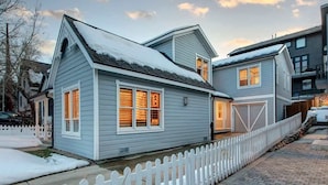 Ett tvåvåningshus med ett vitt staket, ett garage och en uppfart.