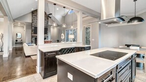 A modern kitchen with a central island, built-in appliances, and pendant lighting. - Yourcation® Awaits in Majestic Mountain Home! (Fairview)