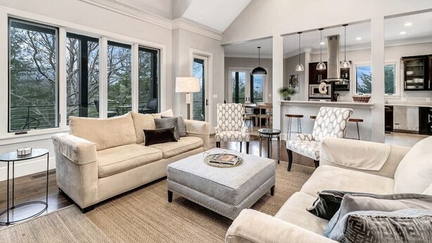A spacious living room with a large window, a sofa, a coffee table, and a dining area. - Yourcation® Awaits in Majestic Mountain Home! (Fairview)