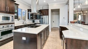 A modern kitchen with stainless steel appliances, a large island, and dark wood cabinets. - Yourcation® Awaits in Majestic Mountain Home! (Fairview)