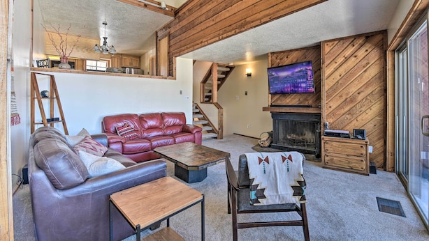 A cozy living room with a fireplace, leather sofa, and a television. - Warm Townhome w/ Sauna at Angel Fire Ski Lift (Angel Fire)