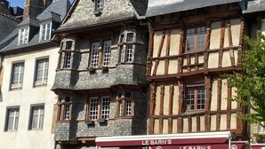 Un edificio tradicional de entramado de madera con una tienda llamada "LE BARN'S" en la planta baja.