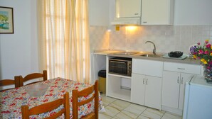 A small kitchen with a table and chairs, a sink, a stove, and cabinets.