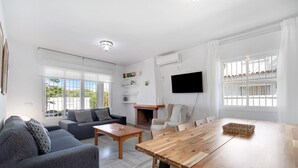 Ein modernes Wohnzimmer mit einer Couch, einem Couchtisch, einem Esstisch und einem Kamin.