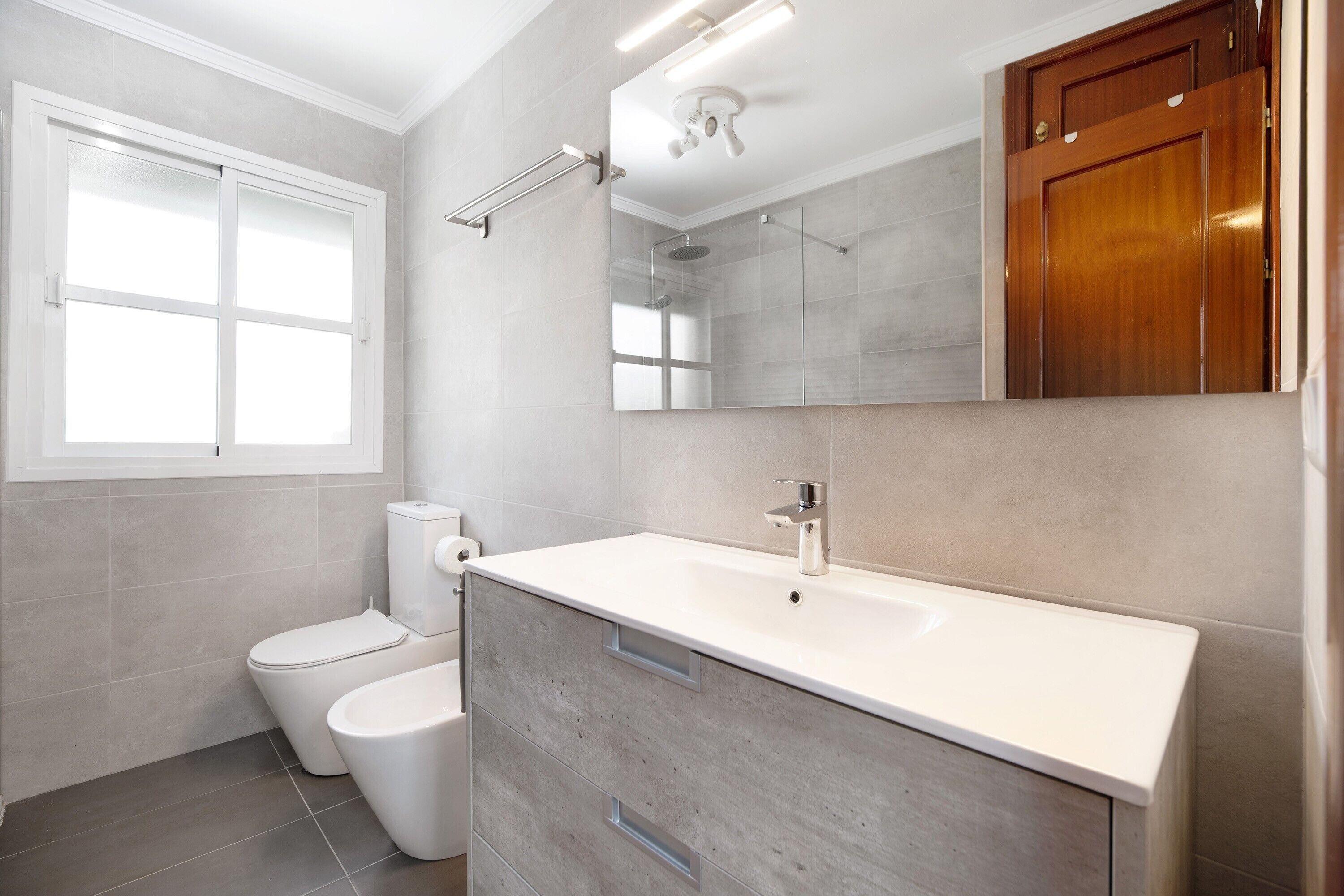 Une salle de bain moderne avec un lavabo blanc, des toilettes et une douche.