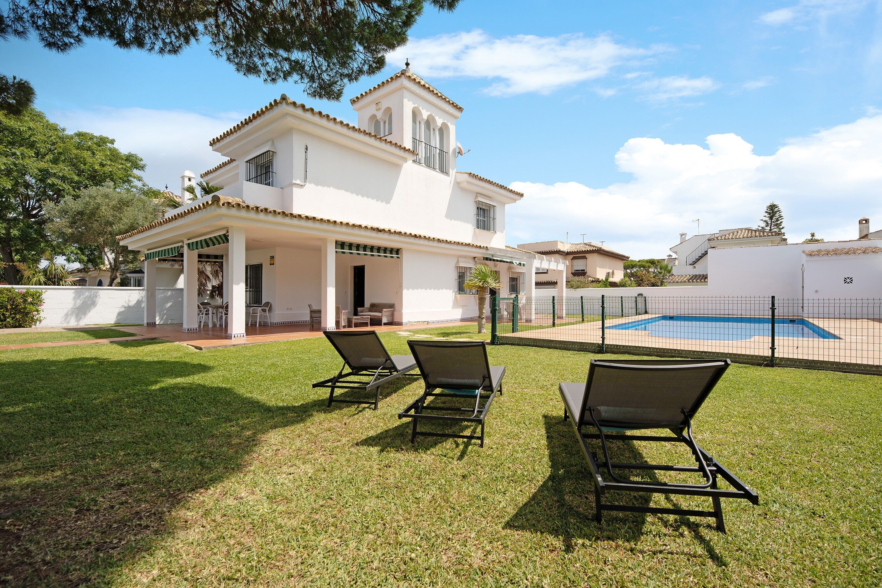 Une maison à deux étages avec une piscine, un espace salon extérieur et un patio couvert.