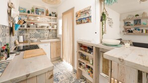 Una cocina con armarios de madera, salpicadero azulejado y diferentes utensilios de cocina en estantes.