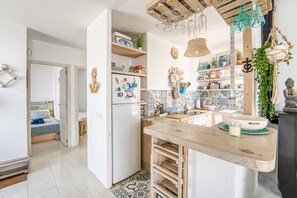 Een kleine keuken met een houten aanrecht, een koelkast en een betegelde achterwand.