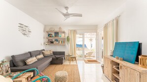 Una sala de estar con un sofá, una mesa de centro, un televisor y un aparador de madera.