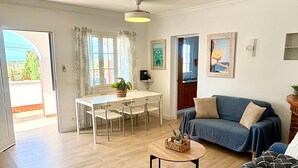 Een woonkamer met een bank, een salontafel en een eethoek met stoelen en een tafel.