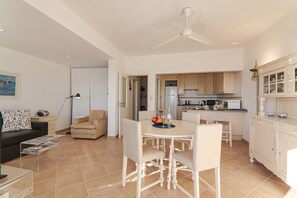 A modern living room with a dining table, chairs, a sofa, and a kitchen area with cabinets and appliances. - Charming Apartment “Sail Away” on the Beach with Sea View & Balcony (Quarteira)