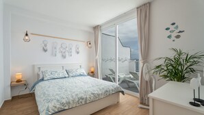Un dormitorio con cama, lámparas de noche, mesita de noche, una planta en maceta y vistas al exterior.