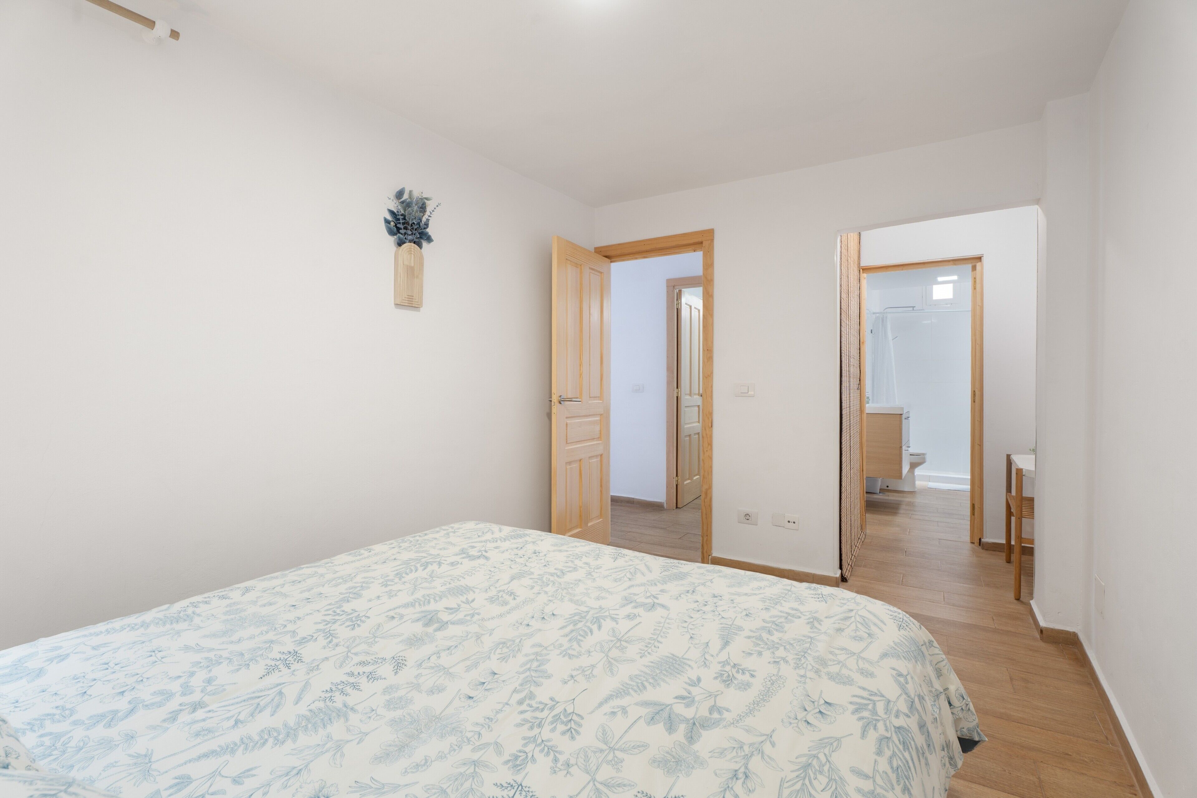 Un dormitorio con cama, una puerta de madera y un baño visible a través de una puerta abierta.