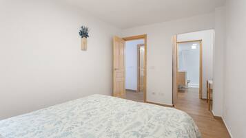 Un dormitorio con cama, una puerta de madera y un baño visible a través de una puerta abierta.