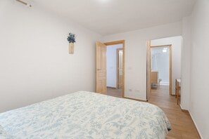 A bedroom with a bed, a wooden door, and a bathroom visible through an open door.