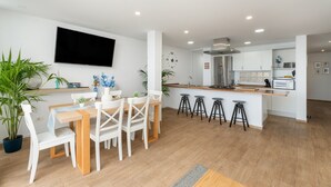 Una cocina moderna con una isla central, taburetes de bar y una zona de comedor con mesa y sillas.