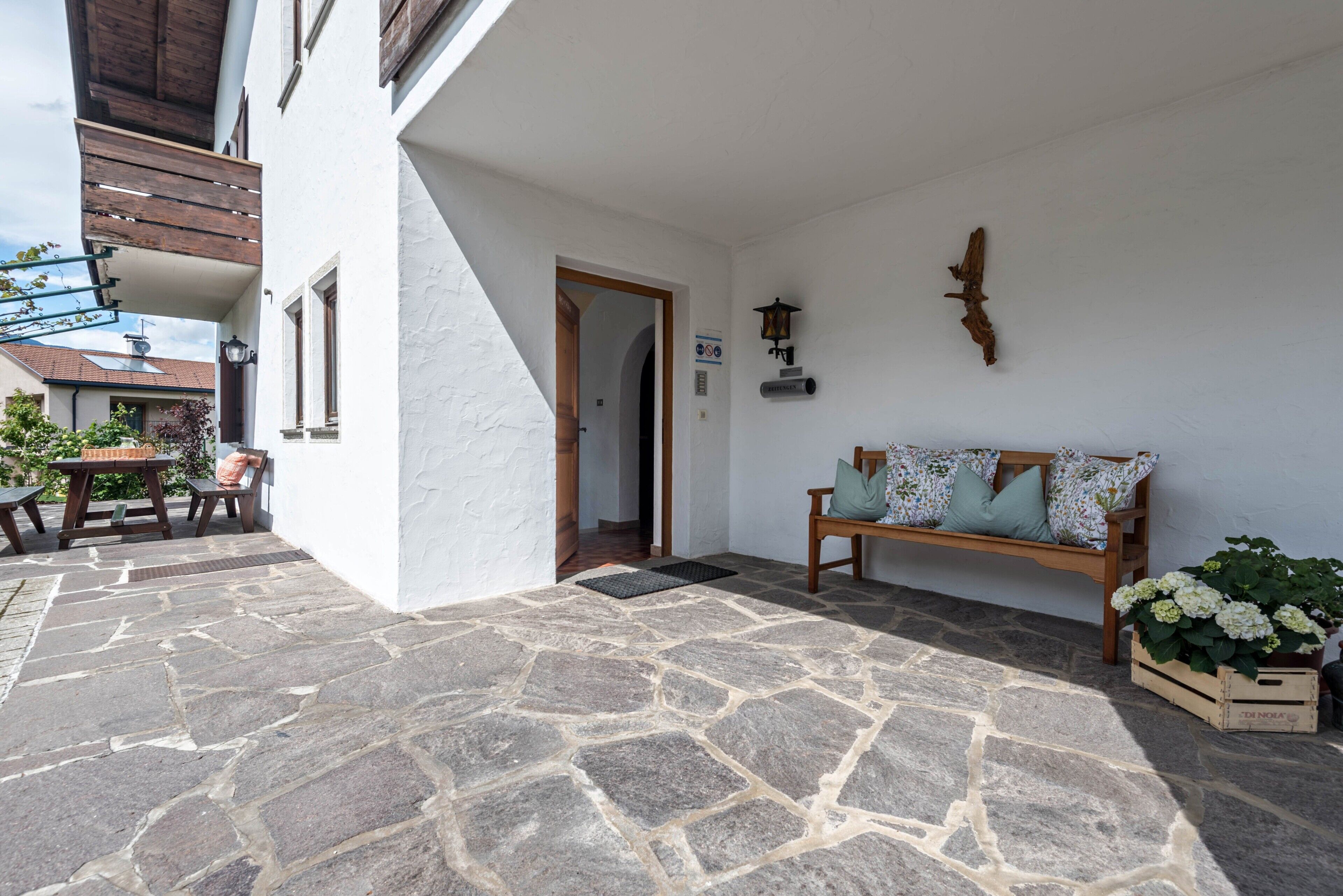 A stone-floored patio with a wooden bench and a potted plant.