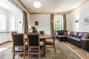 A dining area with a round table and chairs, a sofa, and a patterned rug. - Villa Martiner Apartments Francesco with Mountain View, Balcony & Wi-Fi (Ortisei)
