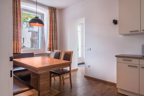 Une cuisine moderne avec une table à manger en bois, des chaises et un luminaire suspendu.