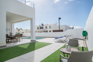 Un espace piscine aménagé sur le toit, avec des chaises longues, une table et une vue sur les bâtiments environnants.