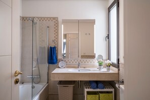 Une salle de bain avec une baignoire, une douche, un lavabo et un miroir.