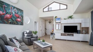 Ein modernes Wohnzimmer mit Sofa, Sesseln und einem Flachbildfernseher auf einer weißen Unterhaltungsecke.