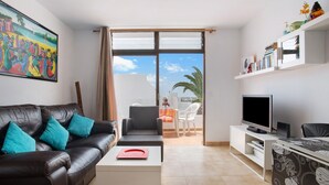 Una sala de estar con un sofá de cuero, un televisor de pantalla plana y un balcón con vistas.