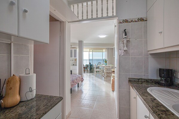 A kitchen with a granite countertop, a sink, and a dining area with a table and chairs.