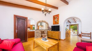 Una sala de estar con una mesa de madera, un sofá rojo, una chimenea de piedra, armarios de madera y un televisor.