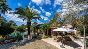Un patio con mobiliario exterior, una piscina y vegetación circundante.