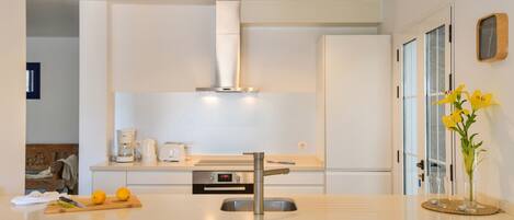 A modern kitchen with a stainless steel sink, a built-in oven, and a range hood.