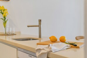 Een keuken met een roestvrijstalen spoelbak, een houten snijplank met een citroen en een witte handdoek.