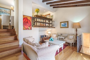 A spacious living area with a sofa, coffee table, and a staircase leading to an upper level. - Charming Villa “Villa Almeda” with Sea View, Pool, Wi-Fi, A/C, Terrace, & Garden (Puerto de Andratx)